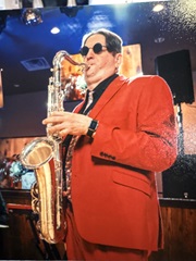 Marcus in a pink suit, playing a silver tenor saxophone